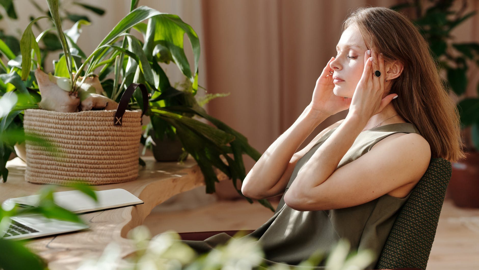 woman sitting while massaging her temple - histamine intolerance and migraine