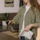 woman in gray coat holding clear glass mug