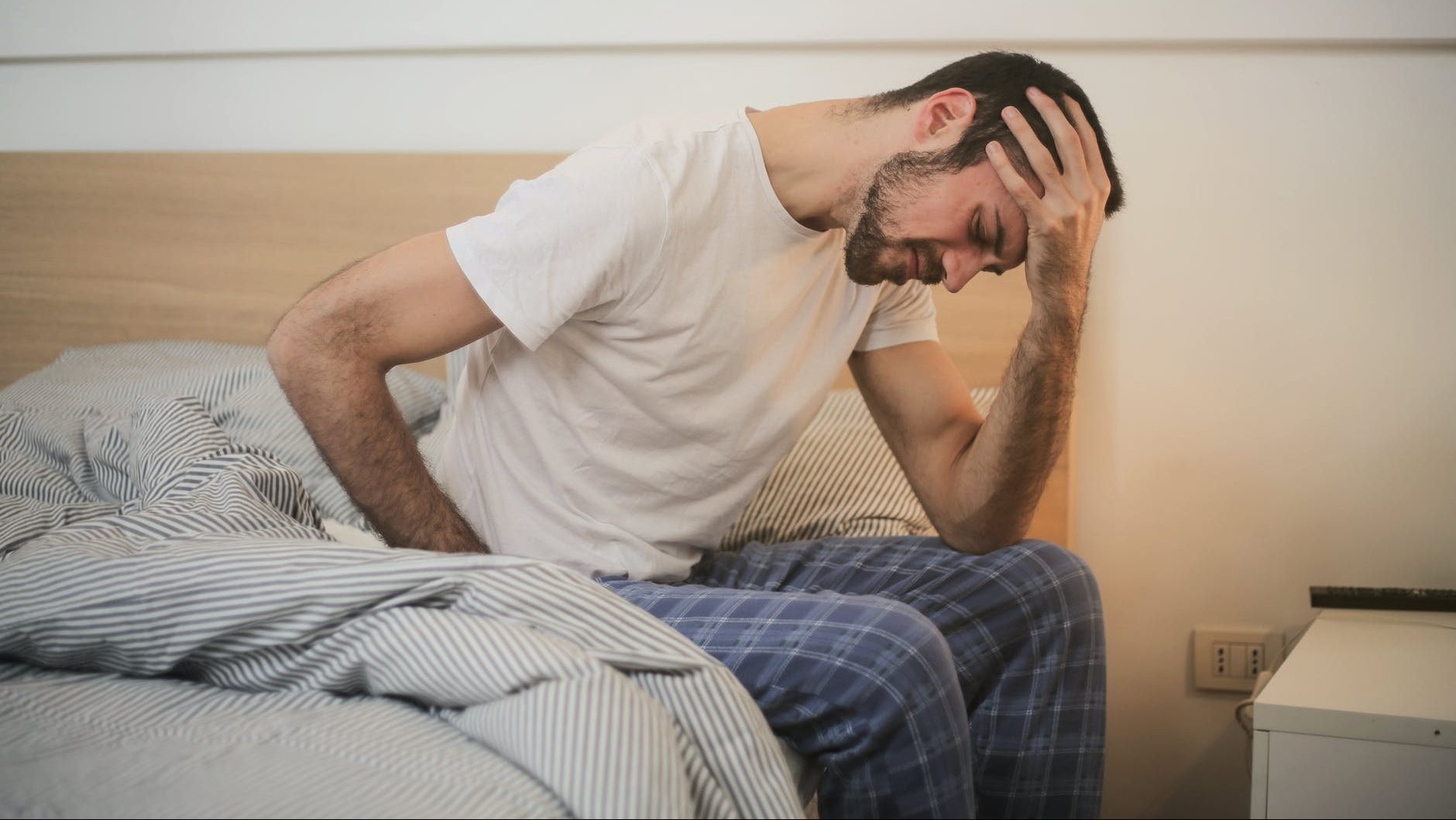 young man in sleepwear suffering from headache in morning