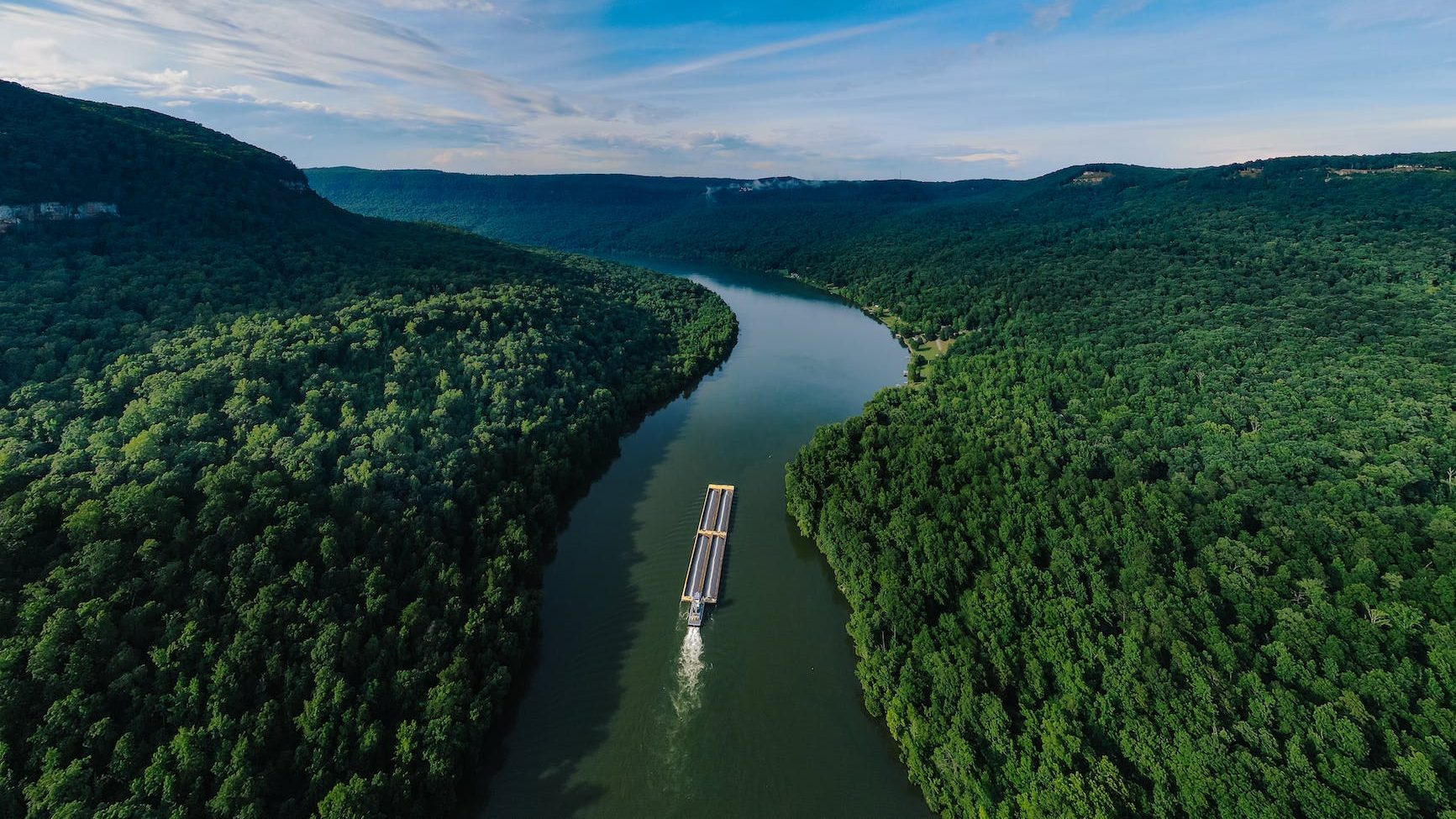 aerial photography of a boat on a waterway in the middle of forest