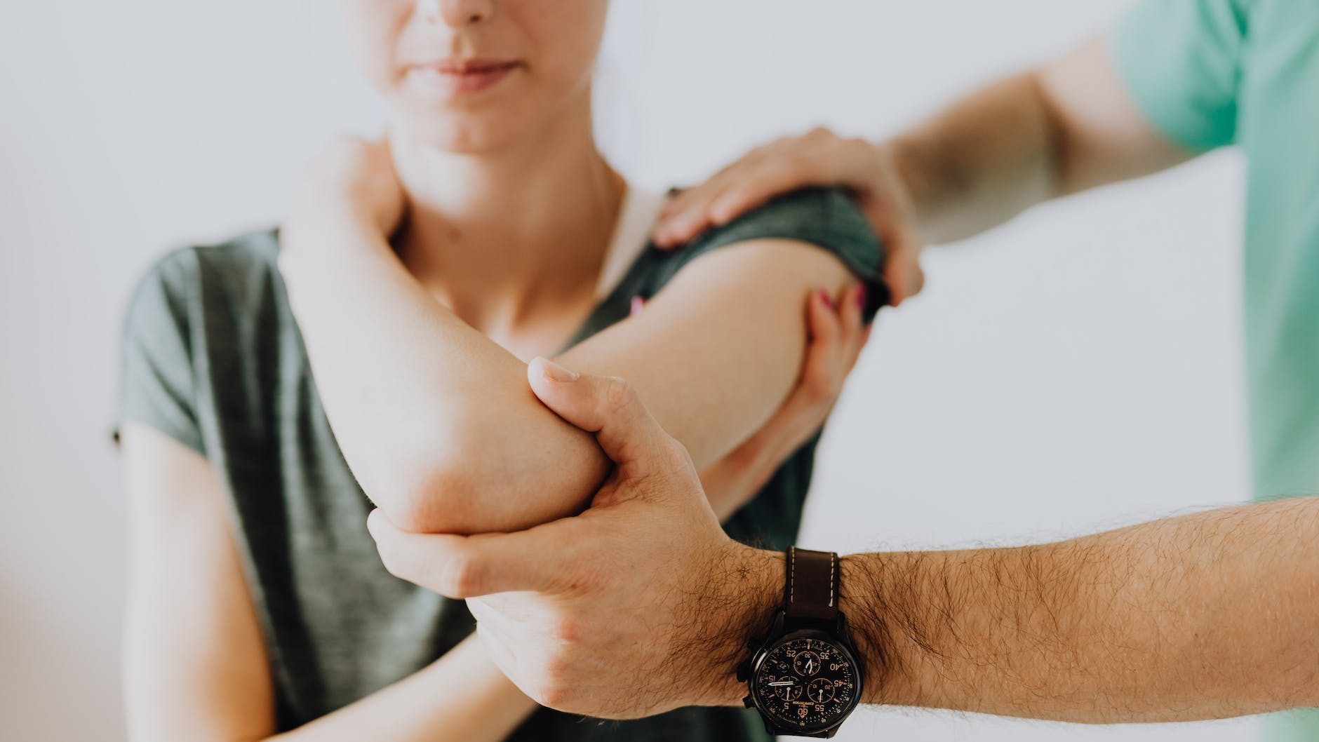 crop unrecognizable chiropractor examining arm joint of female patient